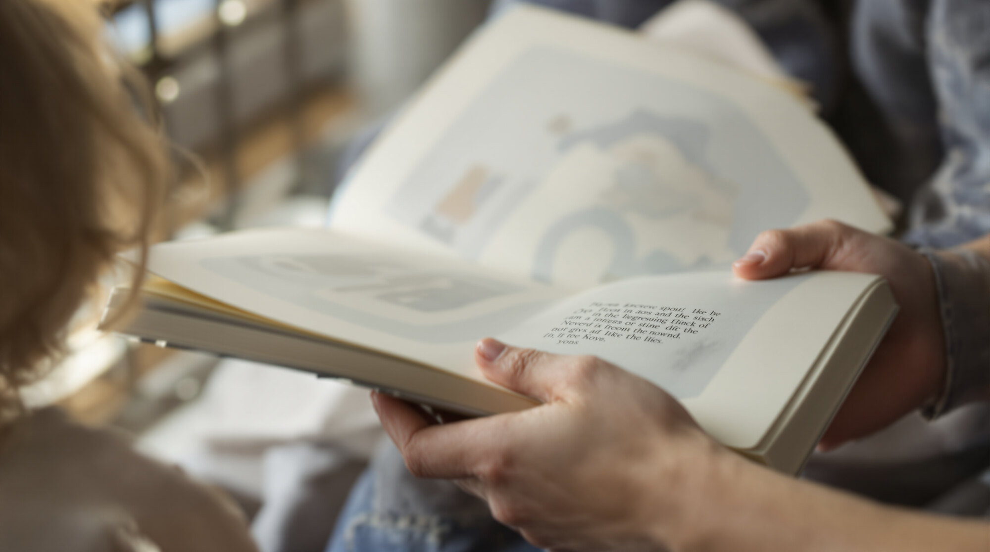 A child and an adult holding an open picture book between them