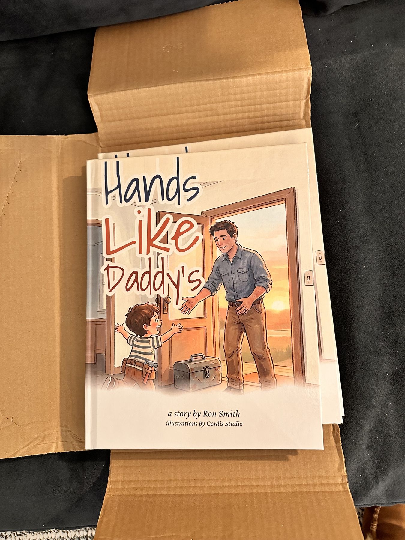 A printed copy of Hands Like Daddy&rsquo;s in its open shipping box